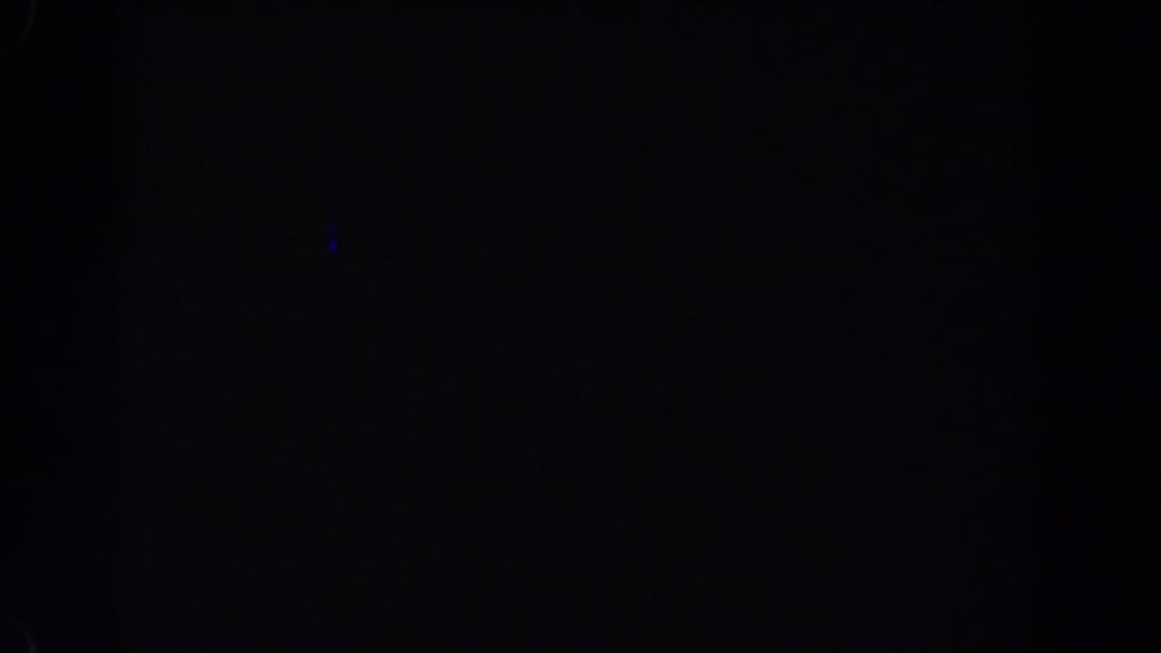 Dark night frame with subtle blue marks and indistinct shadowed shapes.