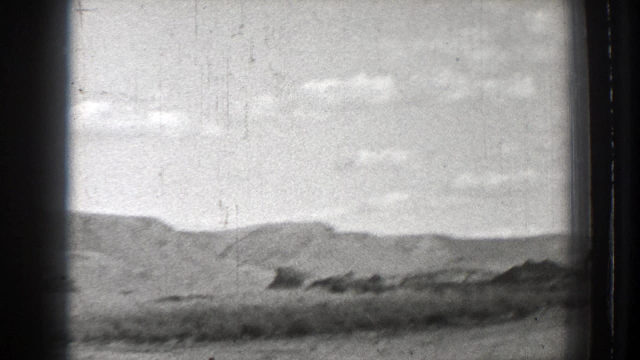 Open hills beneath a cloudy sky with blurred foreground land.