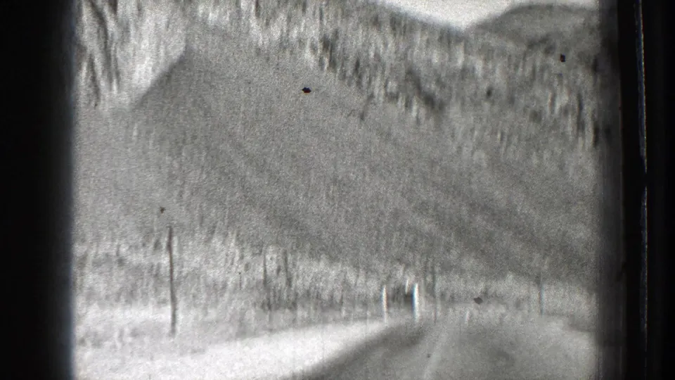 Black-and-white Washington road view from a moving vehicle, with steep slopes and utility poles along the roadside.