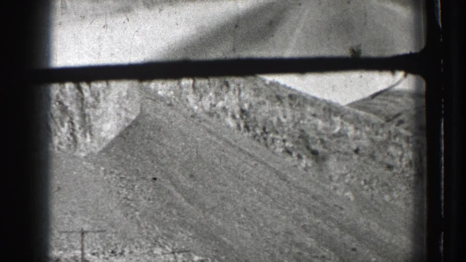 A passing 8mm view of a steep rocky Washington mountainside, framed by dark gate edges and motion blur.