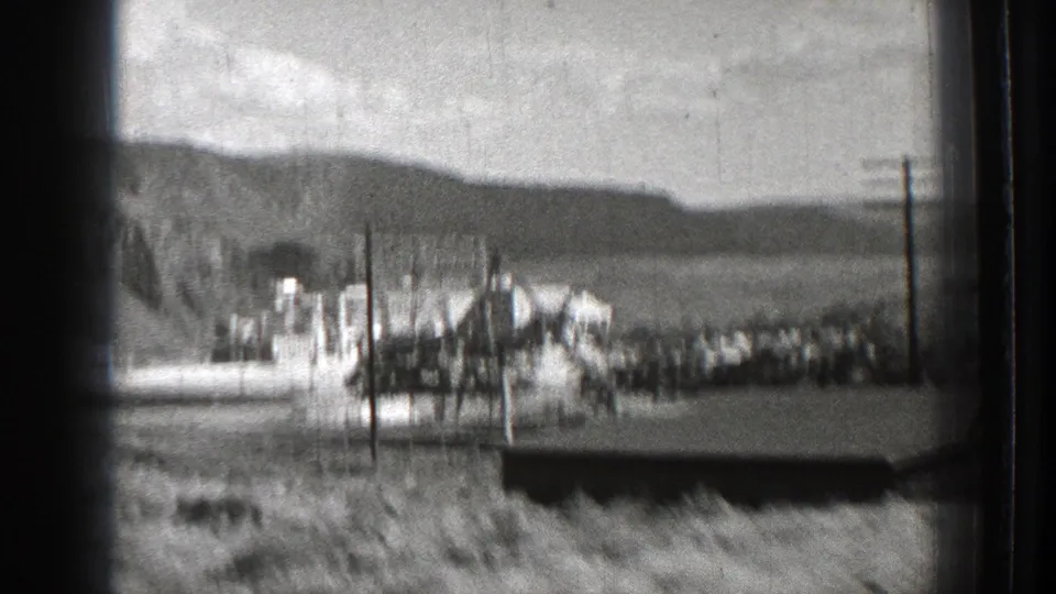 Passing 1939 Washington view of a dam or industrial complex with power poles, fencing, hills, and distant water or valley terrain.
