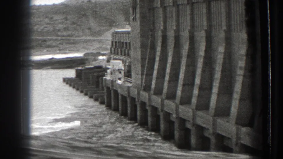 Black-and-white 8mm frame showing a curved wall or dam-like structure near water in Washington, 1939.