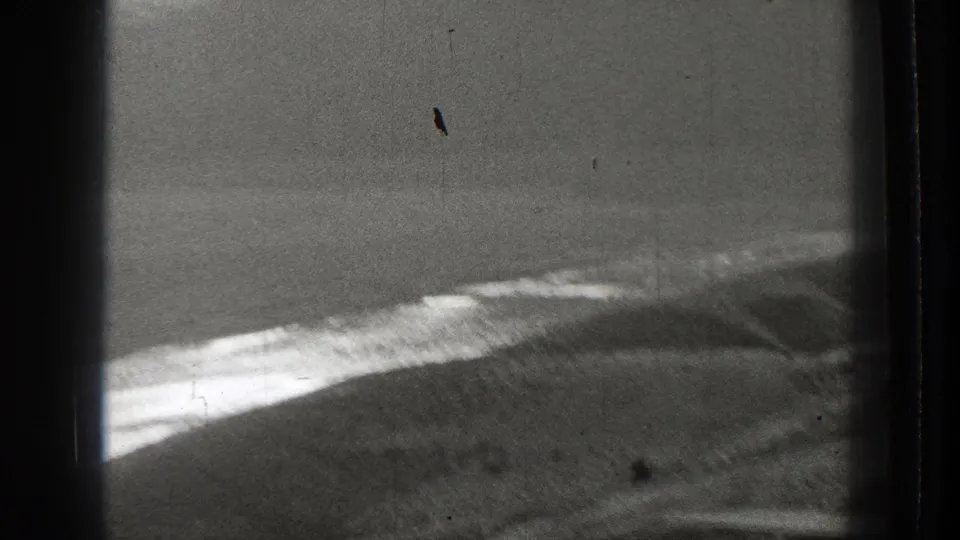 Oblique 1939 Washington 8mm view over a pale water edge and dark hillside, with soft focus and visible film wear.
