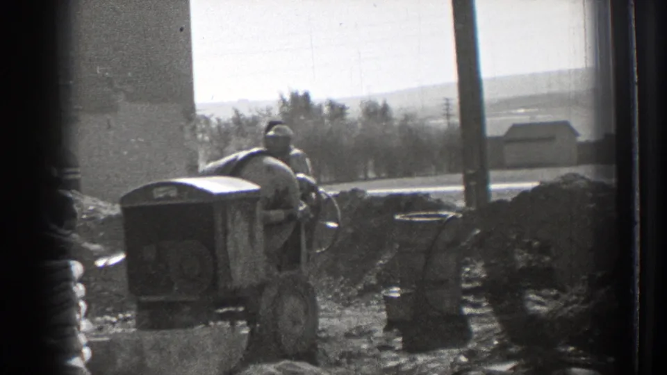 The frame emphasizes the mixer, wheelbarrows, aggregate piles, and a worker partly visible at the edge of the 1939 Washington construction scene.