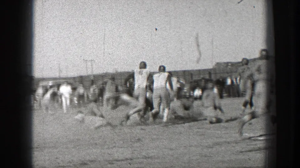 Players and sideline spectators are visible across the field as the football action moves away from the original line.