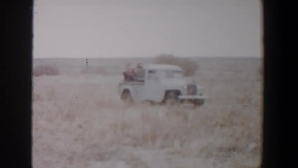 The pickup continues through the dry Lubbock-area landscape, with two riders visible in the open bed.