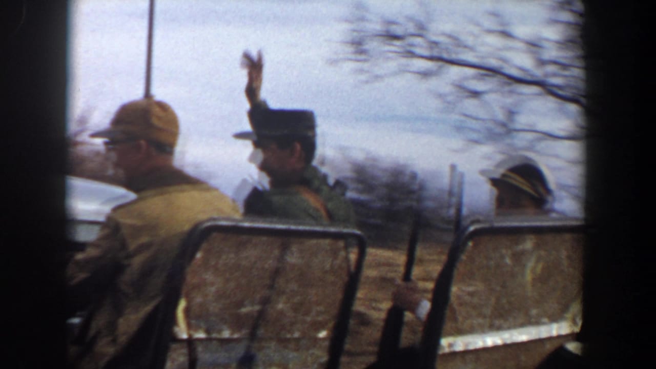 In 1956 Lubbock-area home-movie footage, adult men in hats ride outdoors, with one man waving as the camera passes.