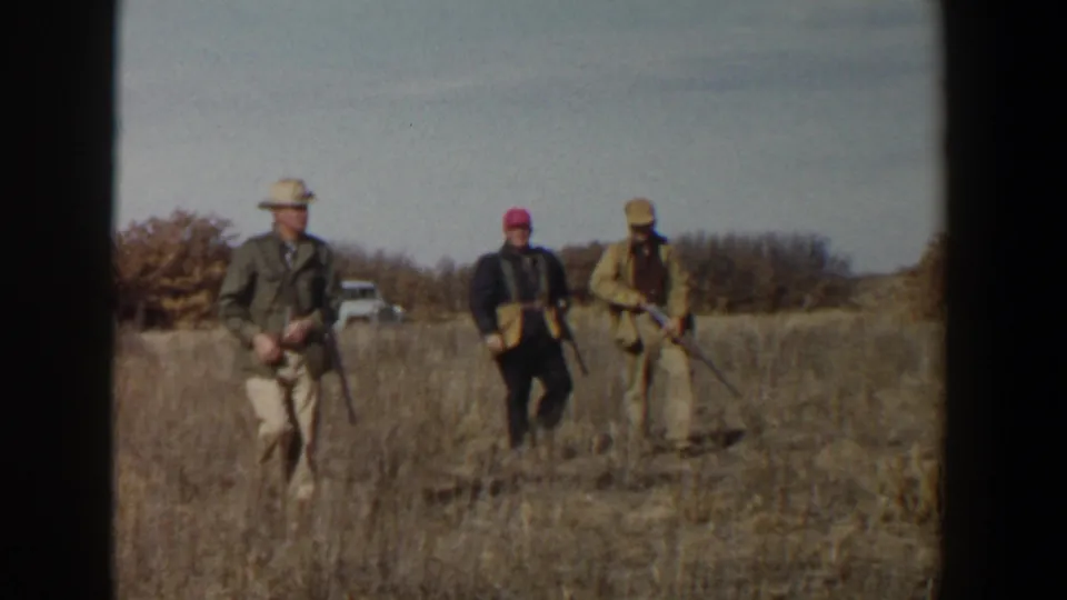 The 1956 Lubbock, Texas footage shows three hunters with rifles walking together through dry grass under a pale sky.