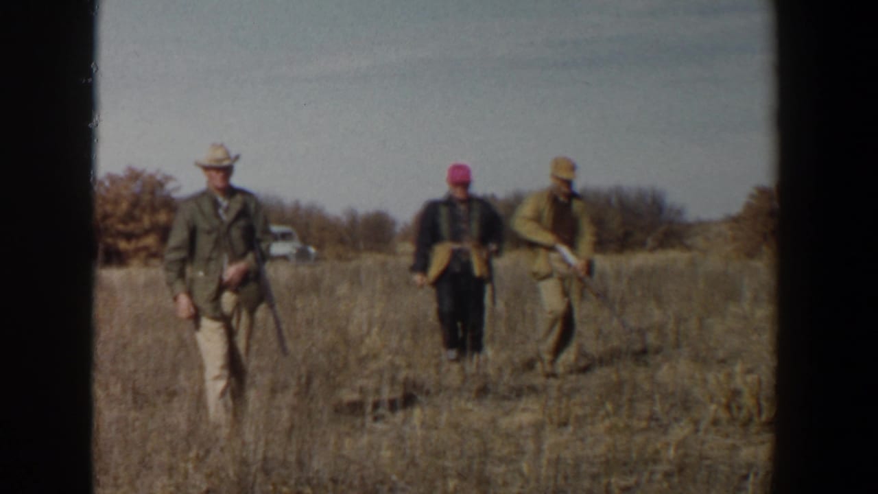 Three hunters walk through a dry field carrying long guns.