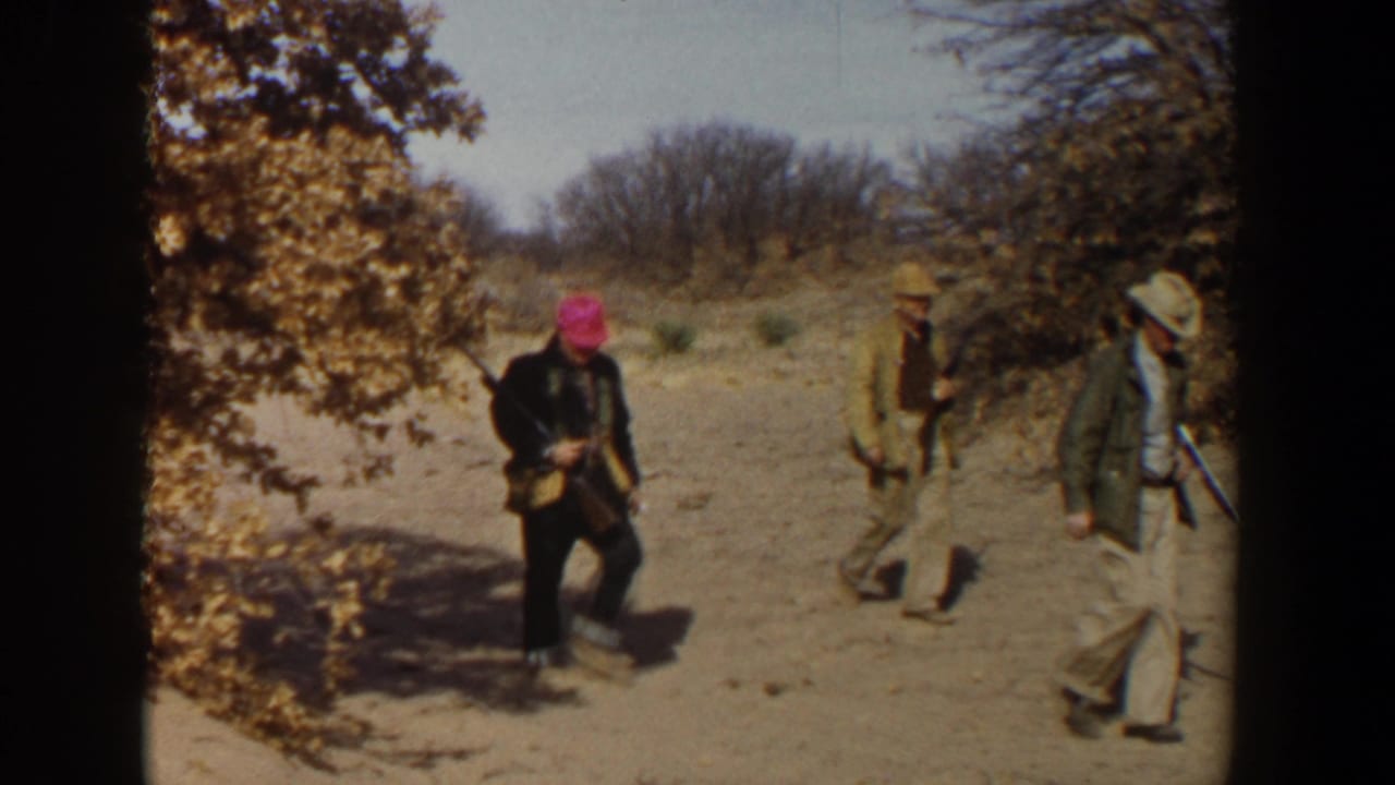 In the 1956 Lubbock, Texas clip, a man with a bright pink head covering enters the group of hunters crossing dry brushland.