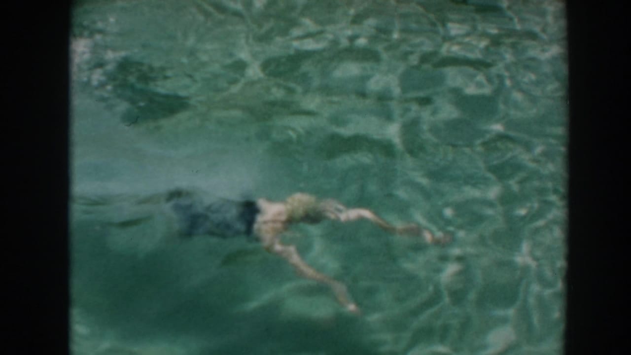 Swimmer moves underwater across a backyard pool after a dive.