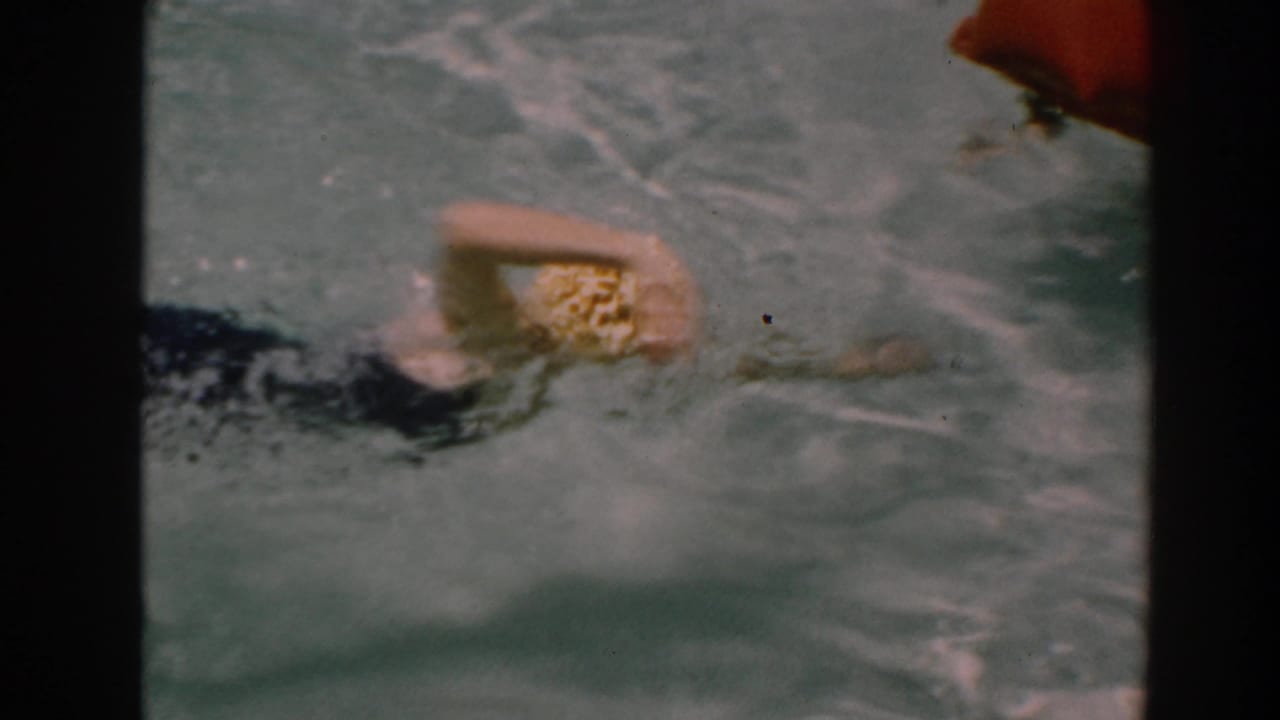 Woman in a yellow swim cap turns her arm through pool water.