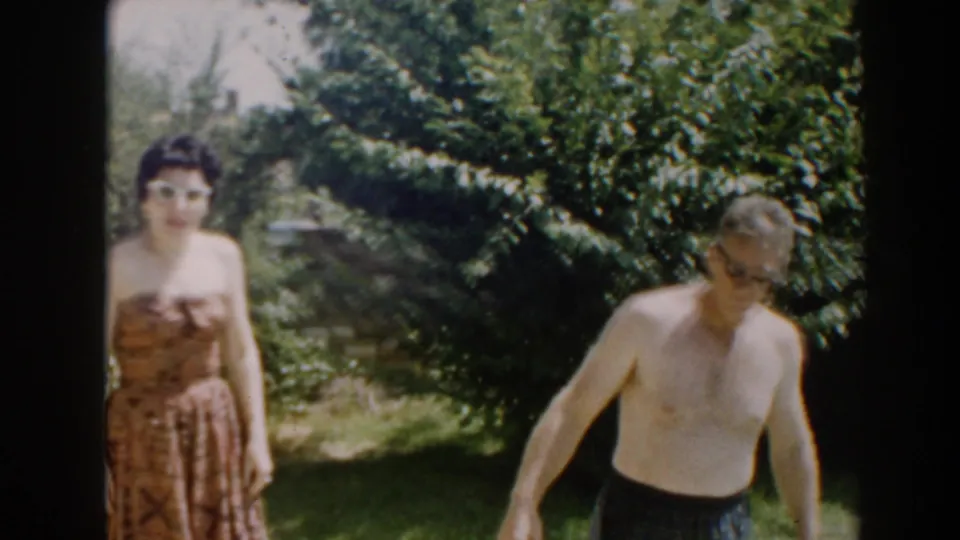 The woman in sunglasses faces the camera in a North Hollywood backyard as the shirtless man moves partly out of frame.