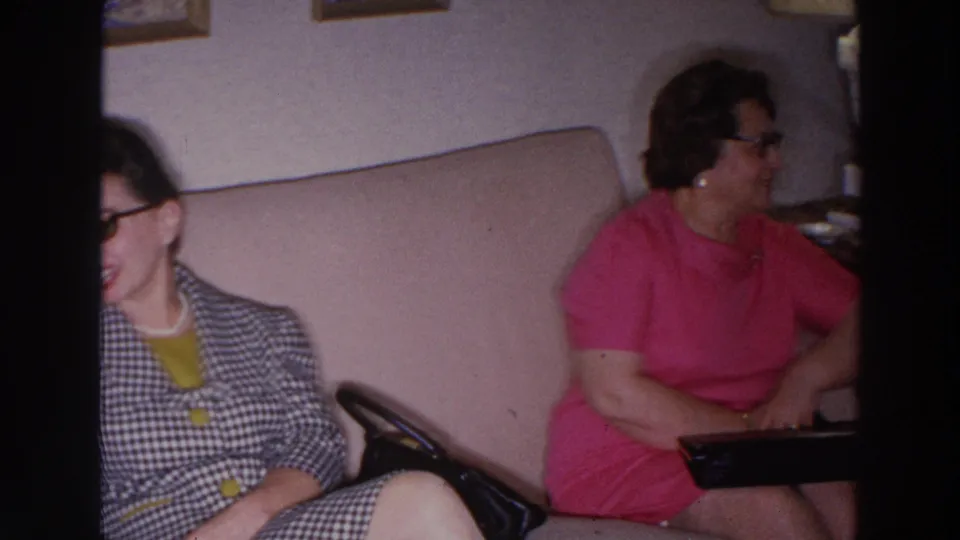 1966 Madison living room frame with seated adults, including a woman in pink and another woman partly visible in patterned clothing.