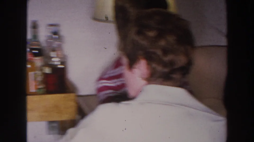 The final frame shows a private room with a seated guest seen from behind, a beige couch, wall lamp, and bottles on a small bar shelf.
