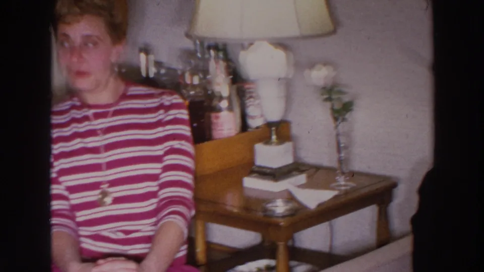 A woman in a red and white striped sweater sits on a sofa in the Madison living room, with a lamp and white flowers nearby.