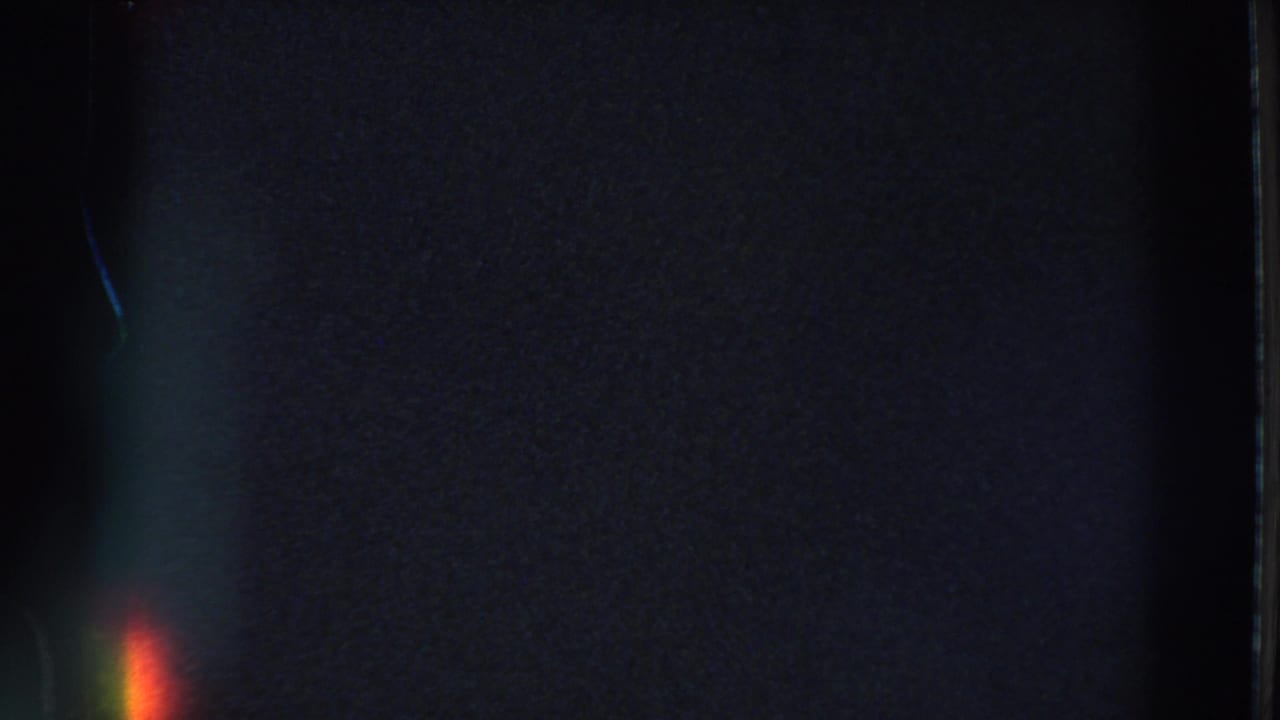 Mostly dark 8mm frame with vertical edge marks and a small glow near the bottom.