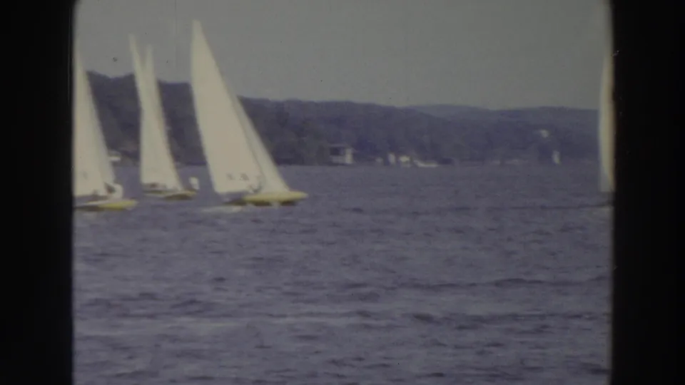 1966 Madison, Wisconsin 8mm frame with multiple sailboats spread across the lake and a yellow-hulled boat among them near the shoreline.