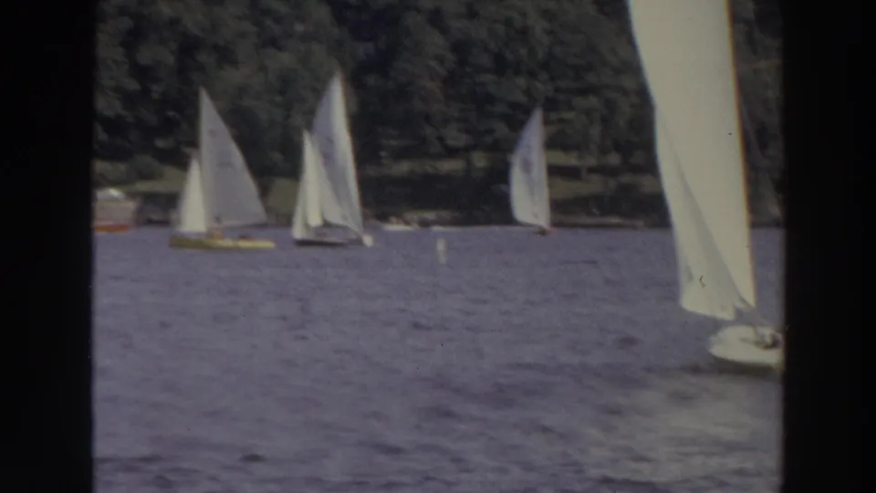 1966 Madison, Wisconsin lake view with several white-sailed boats at varying distances and a sail partly cropped at the right edge.