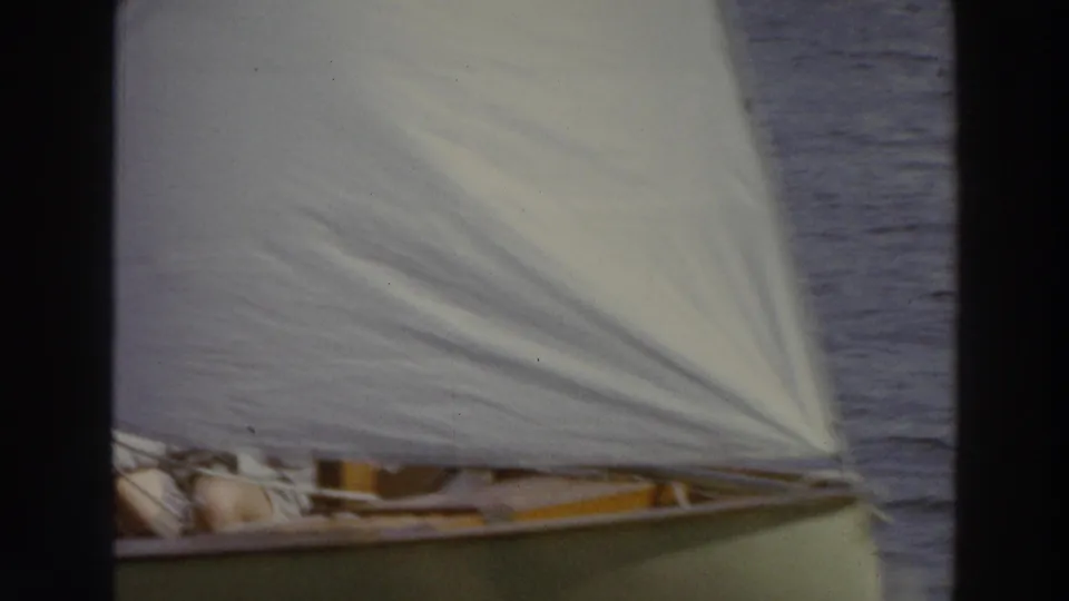 Close 1966 Madison lake footage shows a white sail filling the frame above a green hull with crew partly visible below.