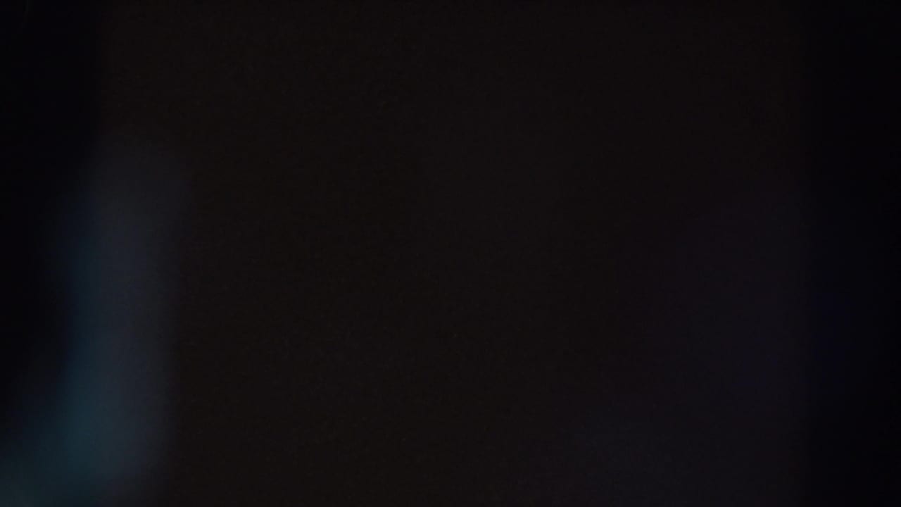 Dark frame with a soft blue vertical flare near the center.