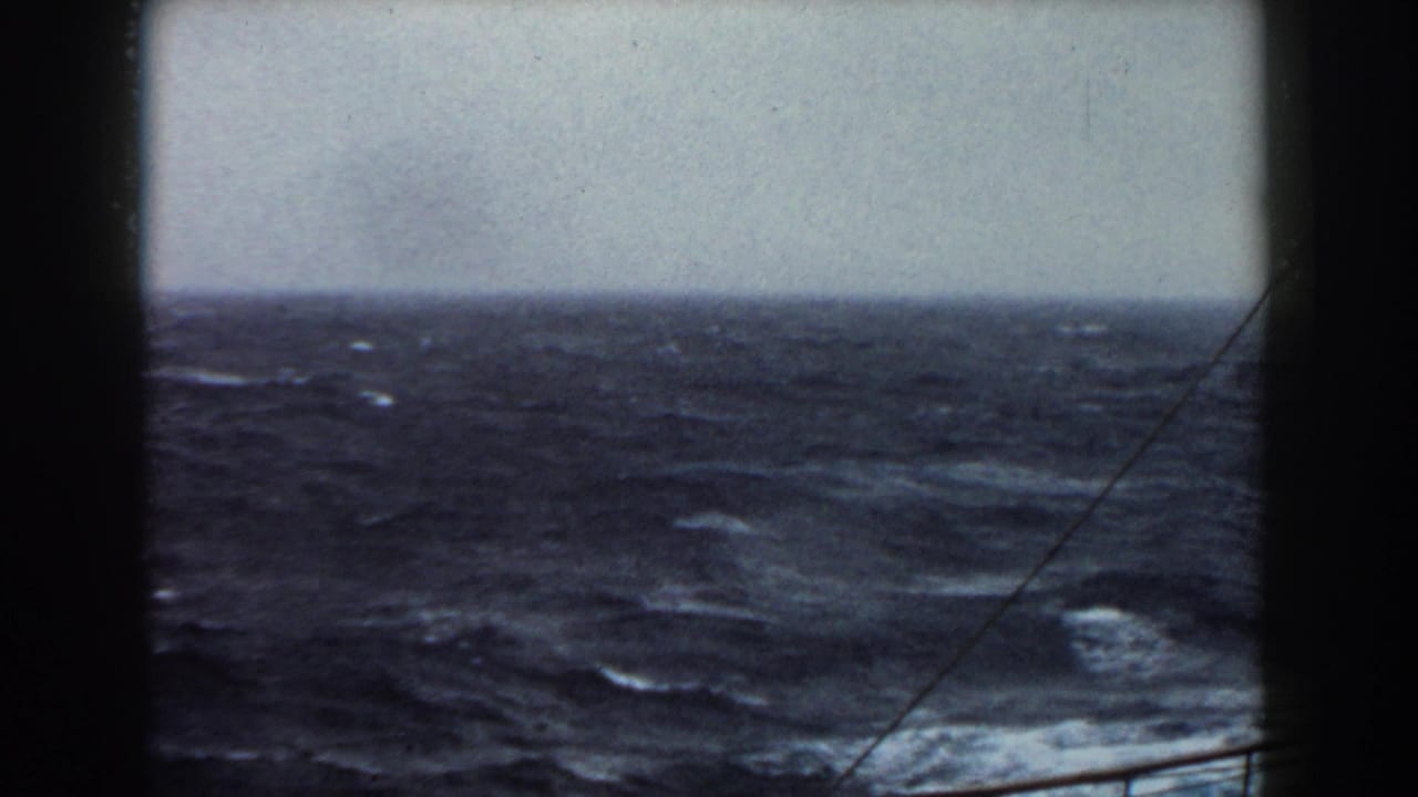 8mm view of rough Atlantic water and horizon from a moving vessel, with dark film or ship edges framing the scene.