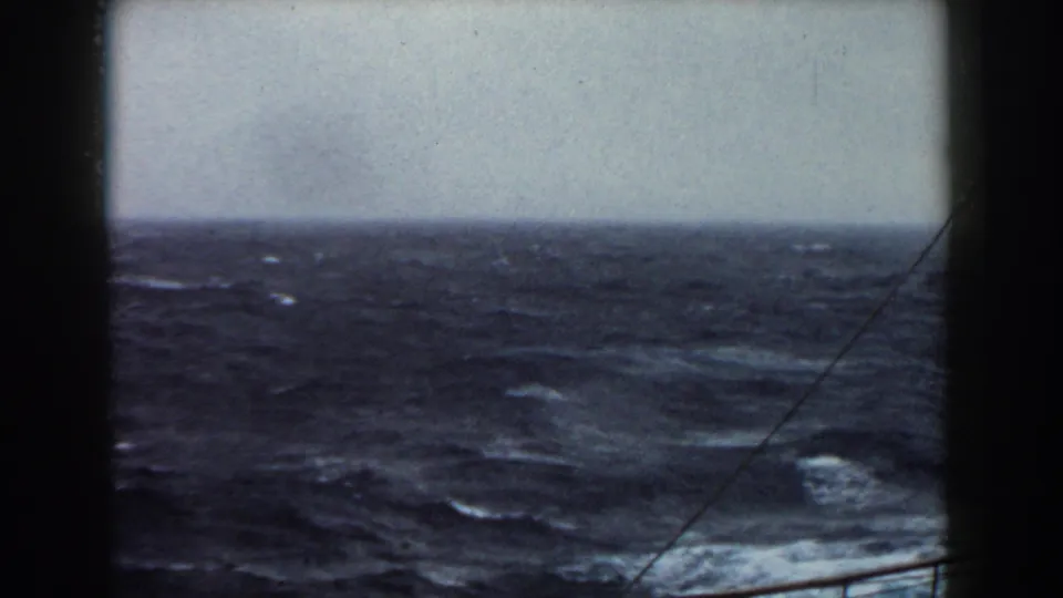 8mm view of rough Atlantic water and horizon from a moving vessel, with dark film or ship edges framing the scene.