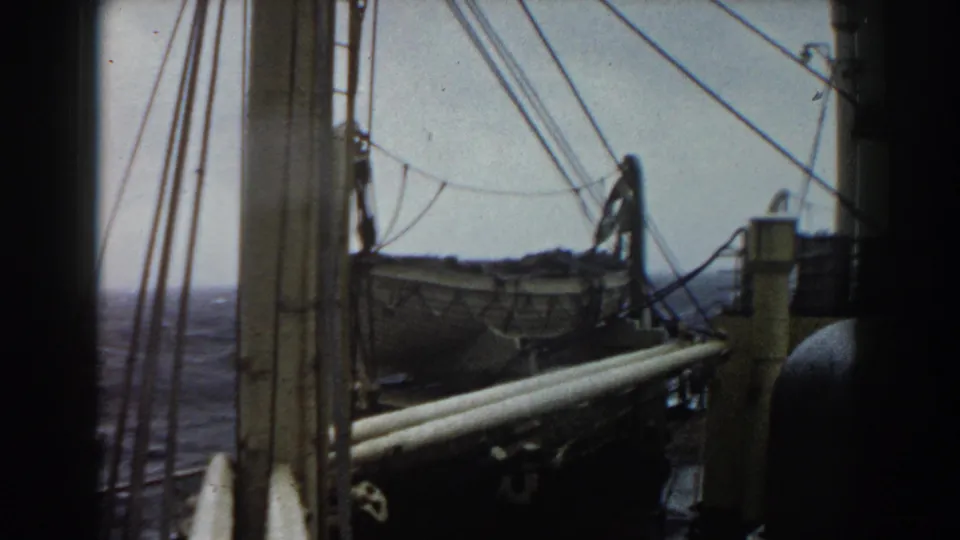 Shipboard deck view showing rigging, a lifeboat, railing, and ocean in the background during a 1959 Atlantic voyage.