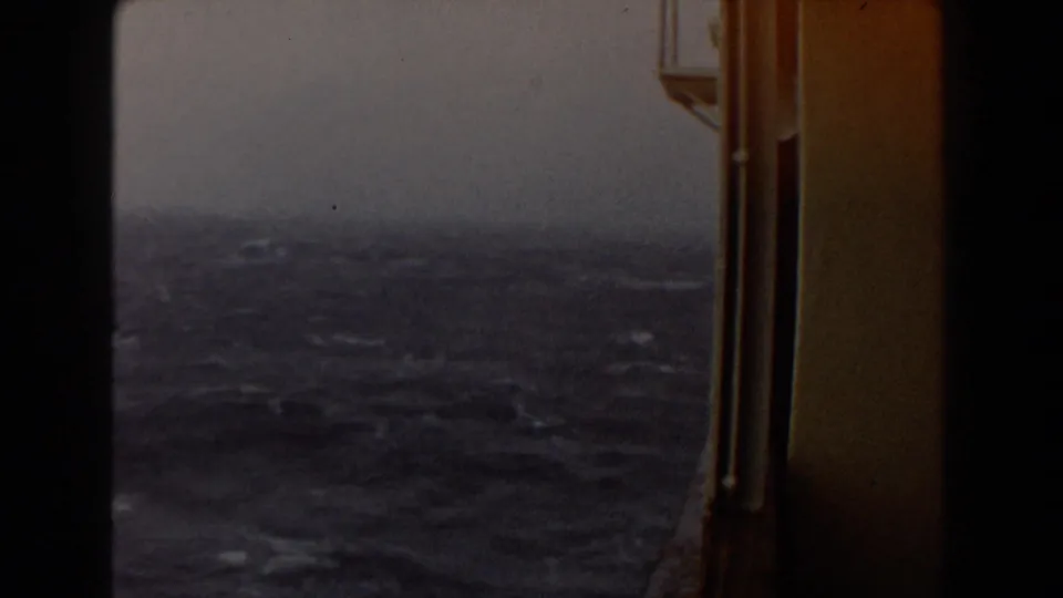 Dim stormy ocean surface seen past a vertical ship window edge, with haze and muted 8mm color in the final frame.