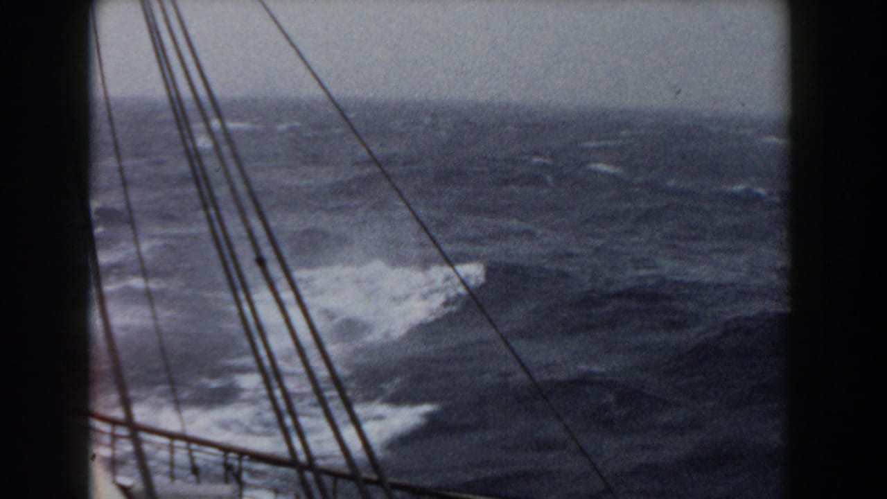 Rough ocean seen past a sailing vessel's rigging and dark frame edges.