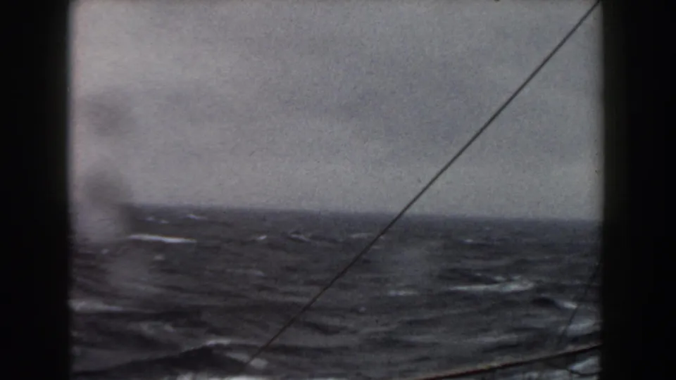 1959 8mm shipboard view of rough Atlantic water under an overcast sky, with rigging lines crossing the frame.
