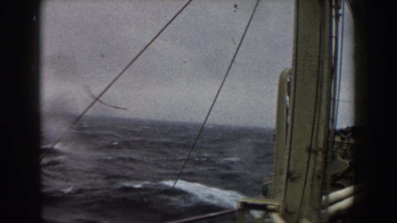 Rough ocean waves and whitecaps seen from a ship through rigging lines and vertical deck structure in archival 8mm footage from 1959.