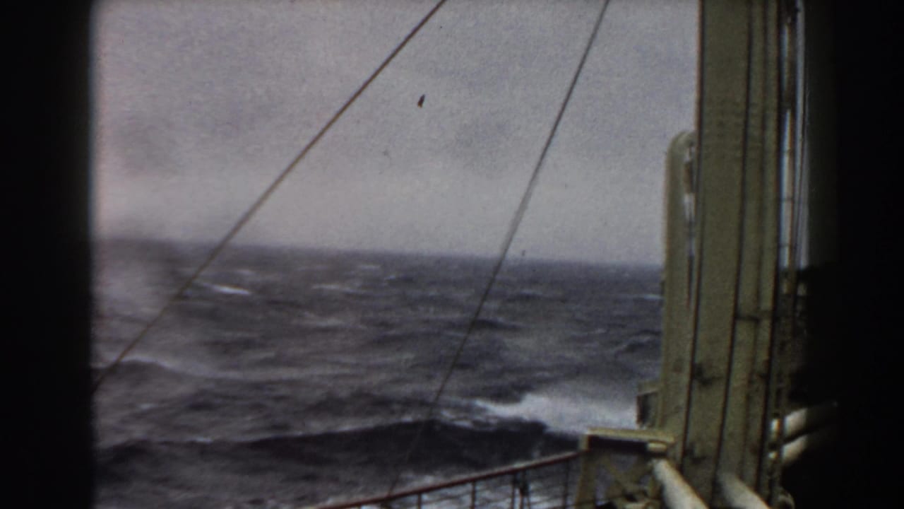 Choppy sea and whitecaps beyond ship railings and rigging lines.