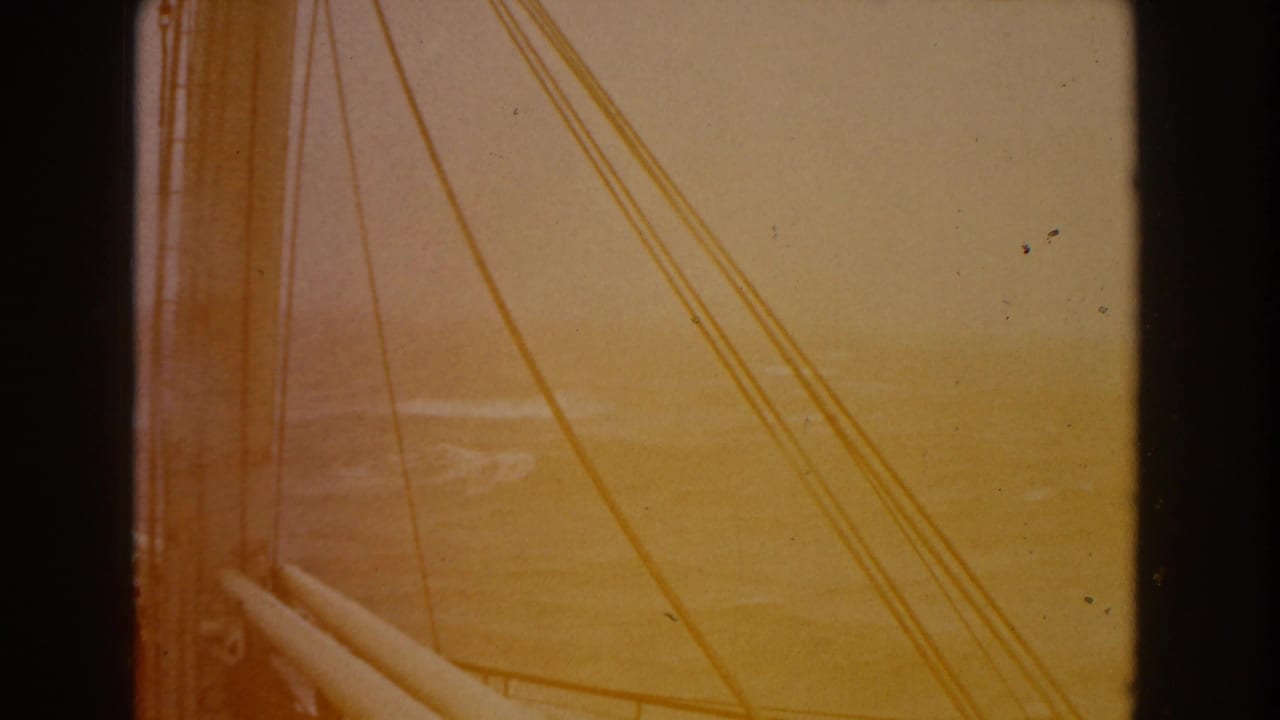 8mm frame looking past sailboat lines toward rough open water under a hazy sky, with a strong warm color cast.