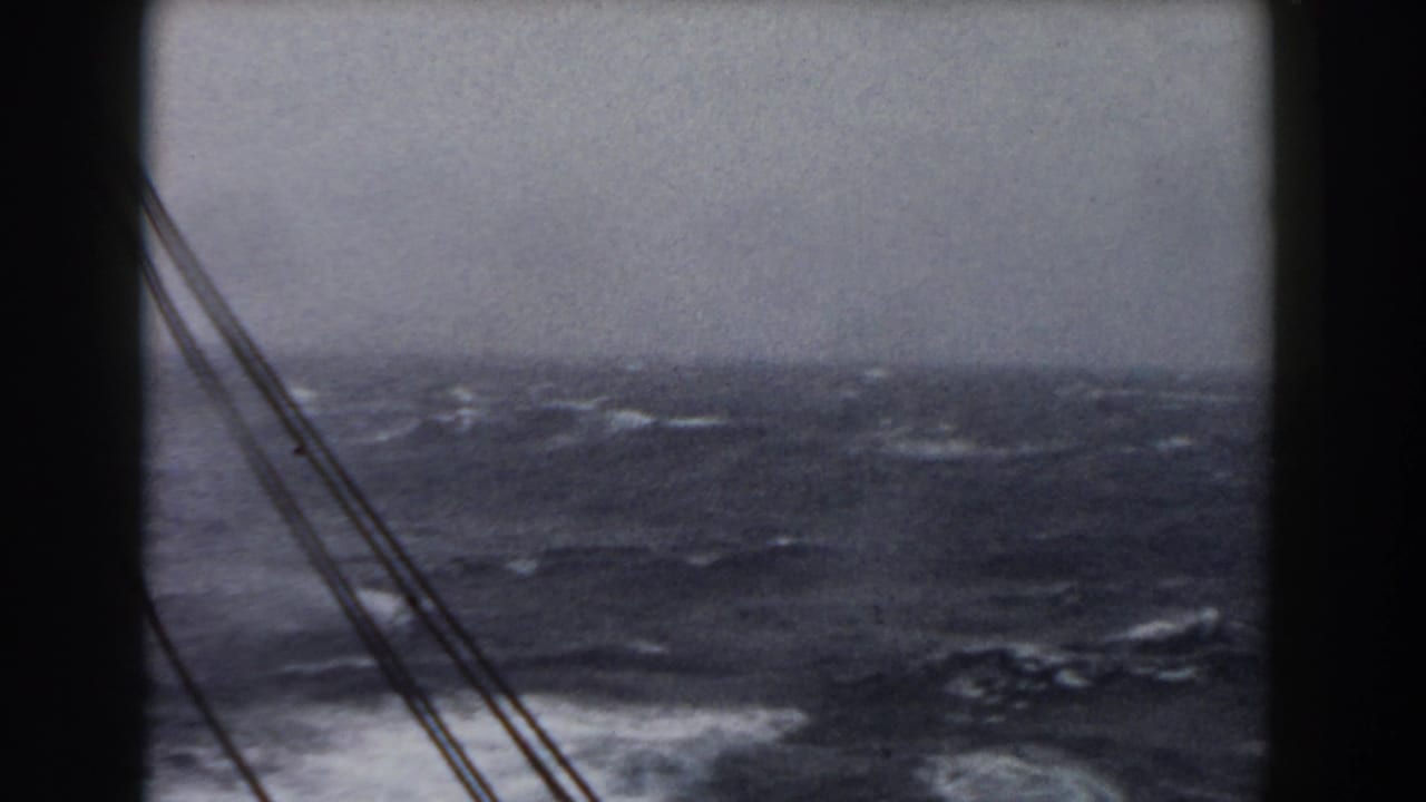 Rough ocean waves seen from a ship with dark rigging lines at the left edge.