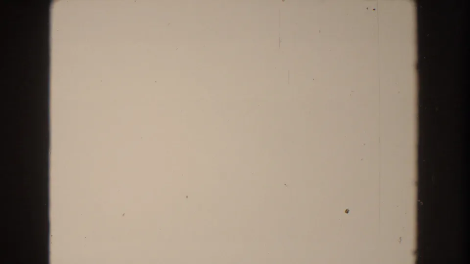 Overexposed 8mm frame with pale field, dark vertical edges, light scratches, dust specks, and minimal sea detail visible.