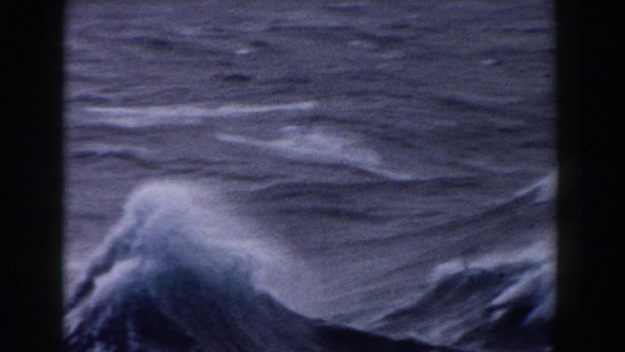 Rough dark ocean waves seen through vertical boat framing.