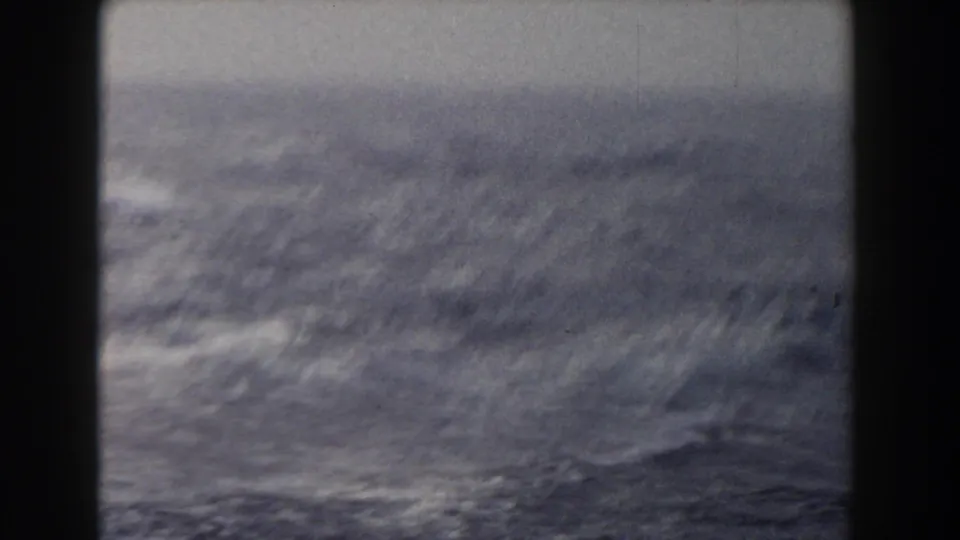 A blurred 8mm view shows rough ocean water and pale spray beyond the boat, suggesting motion and unsettled sea conditions.