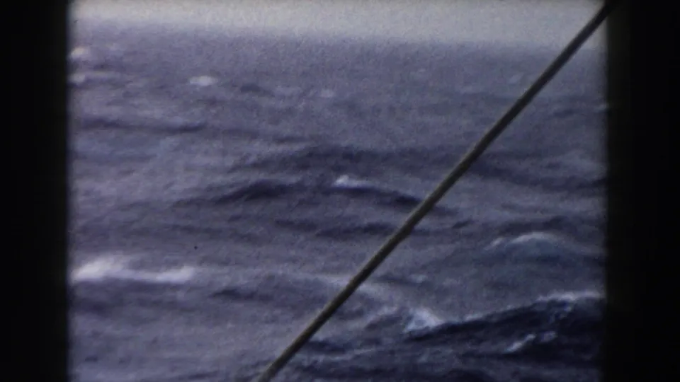 1959 8mm shipboard view of choppy Atlantic water with a diagonal rope or cable in the foreground.