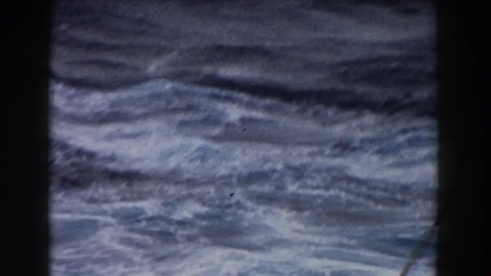 1959 8mm view of rough Atlantic waves and white foam, partly bordered by a dark vertical shipboard edge.