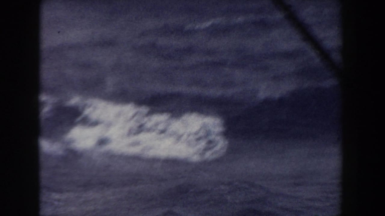 A soft 8mm view of a whitecap or breaking swell on dark blue Atlantic water, bordered by heavy dark frame edges.