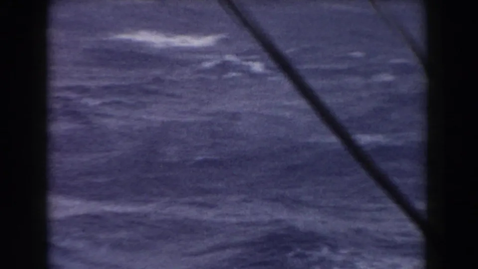 Choppy ocean water seen from inside or beside a boat structure, with a dark vertical edge and diagonal line crossing the frame.