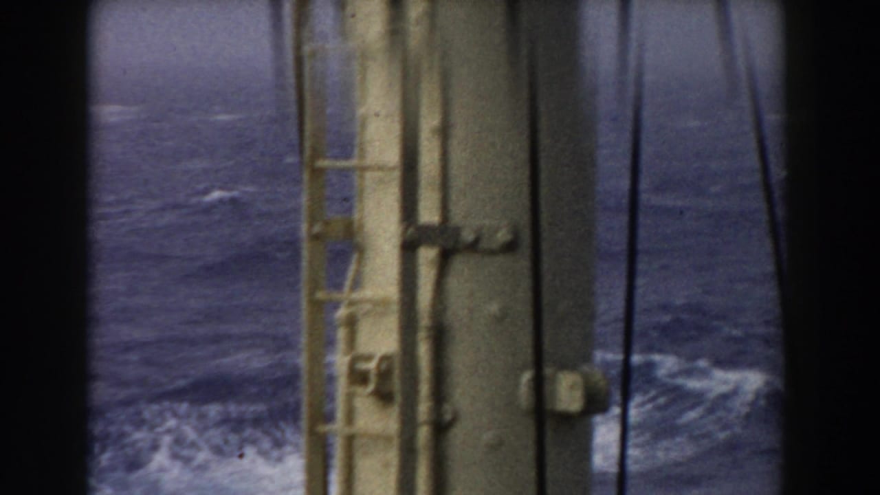 1959 8mm home-movie frame looking over choppy Atlantic water through shipboard metal framework and dark vertical framing.