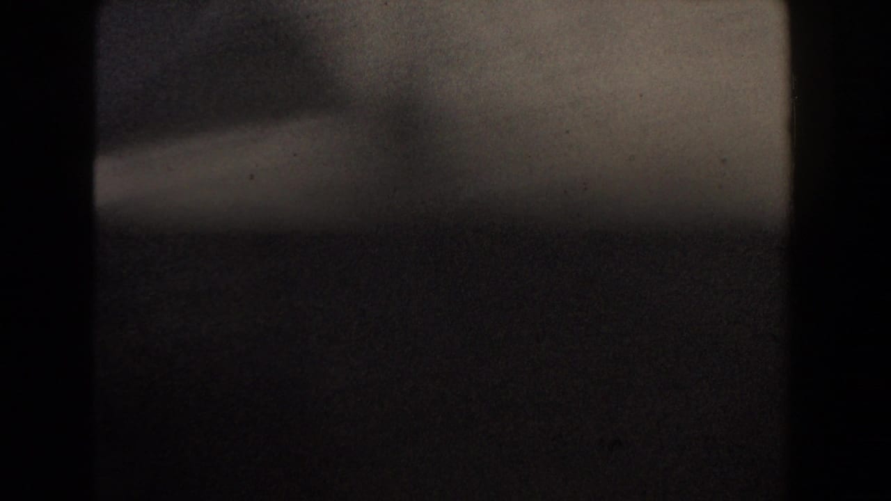 Dark, blurred 8mm frame with a pale band near the top and heavy shadow.