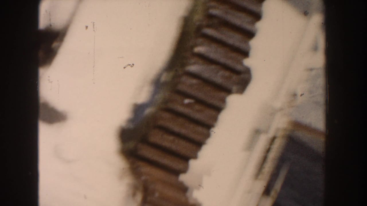 1960 Dearborn 8mm frame with a ribbed brown object crossing a bright background, seen in soft focus with dust marks.