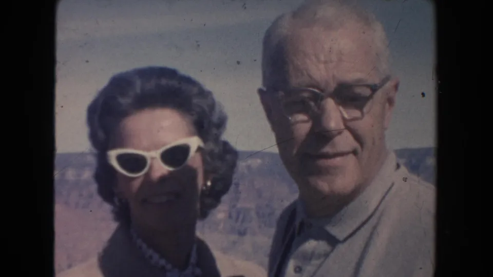 The couple faces the camera in 1962 Arizona, framed from the shoulders up against a distant canyon and pale sky.
