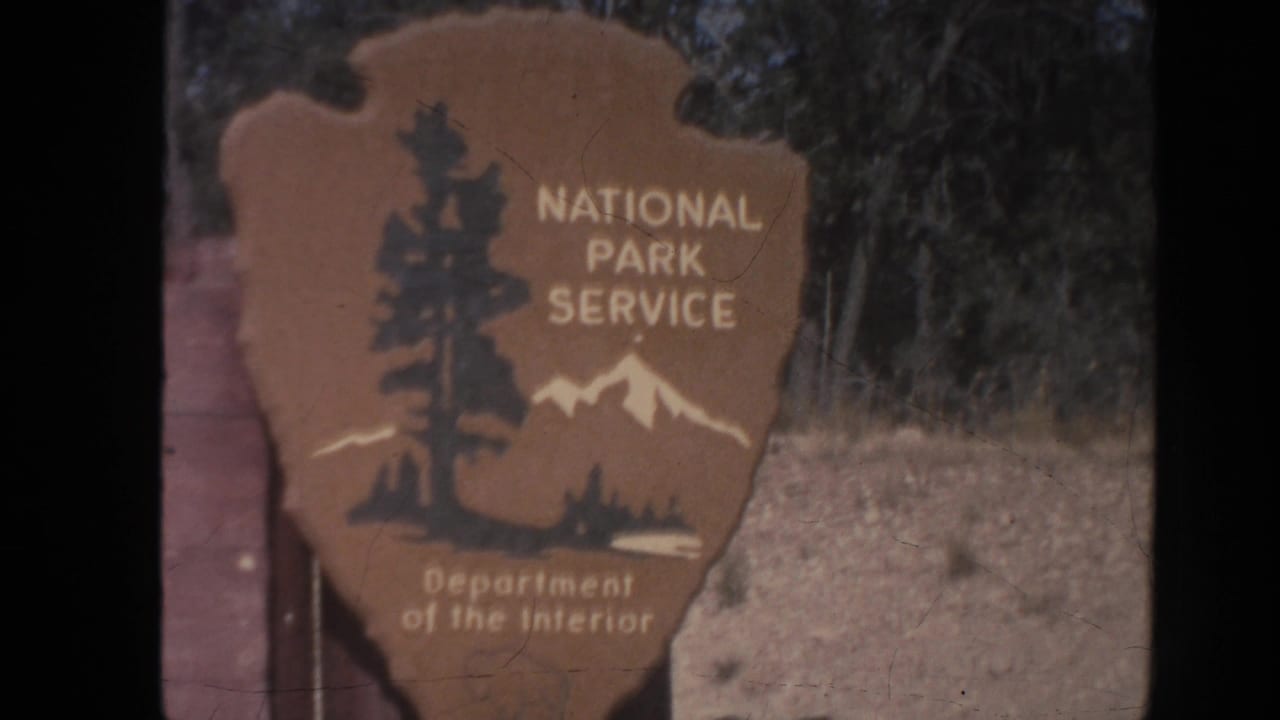 National Park Service arrowhead sign beside a Grand Canyon entrance board.