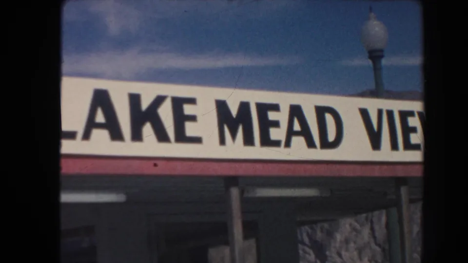 1962 Arizona 8mm frame showing part of a Lake Mead View sign, a street lamp, and blue sky from a visitor-shot angle.