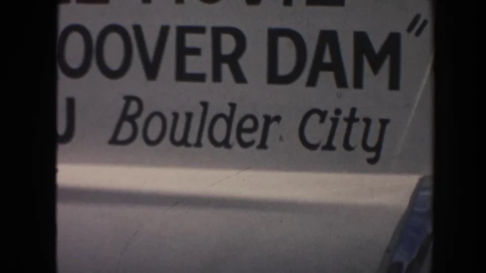 Final 1962 Arizona frame holding on the Hoover Dam movie-ad sign, with Boulder City text and soft faded 8mm color.