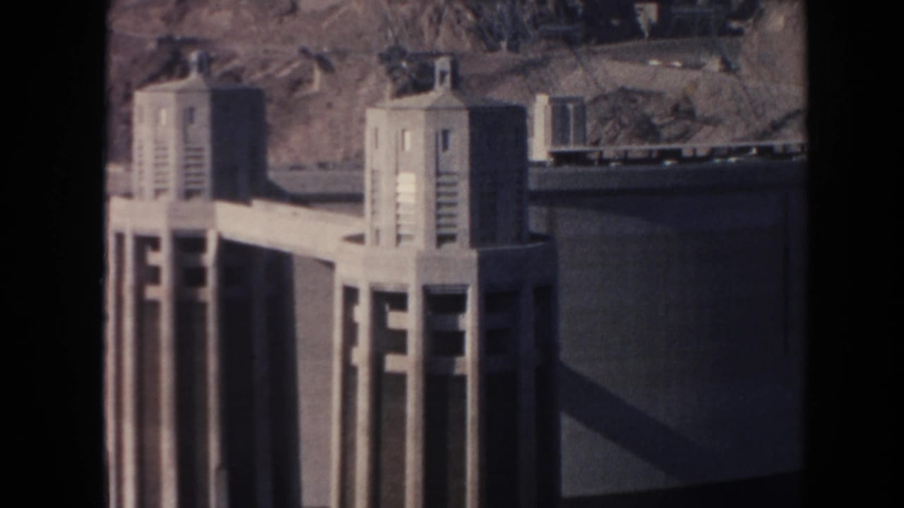 Hoover Dam intake towers beside a concrete wall and rocky slope.